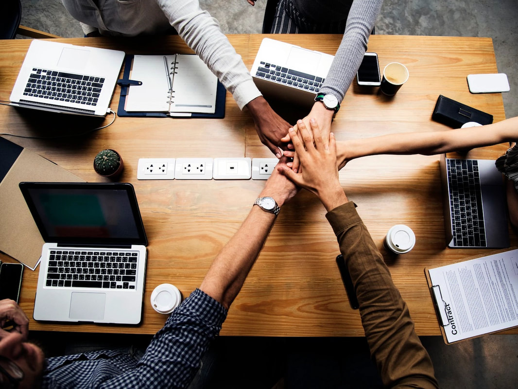 A diverse team joining hands around a work table